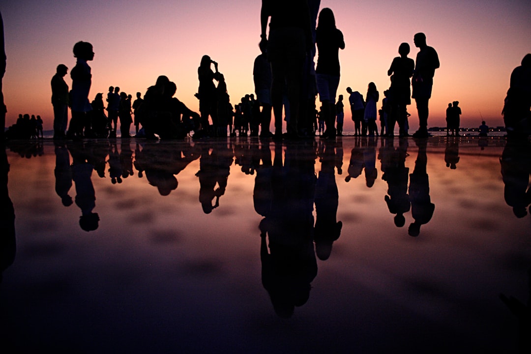 silhouette of people standing on mirror during golden hour silhouette of people standing on mirror during golden hour