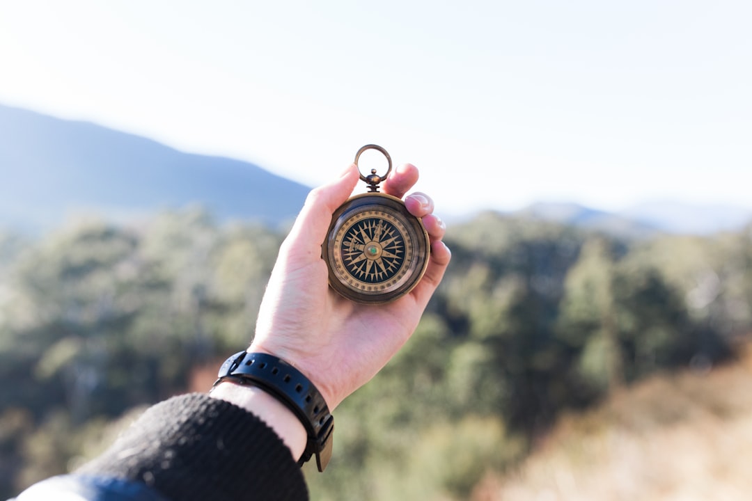 person holding compass selective focus photography person holding compass selective focus photography
