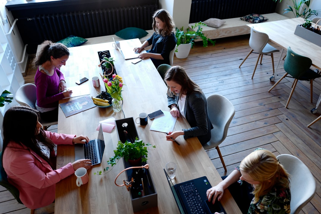 a group of people sitting around a wooden table a group of people sitting around a wooden table