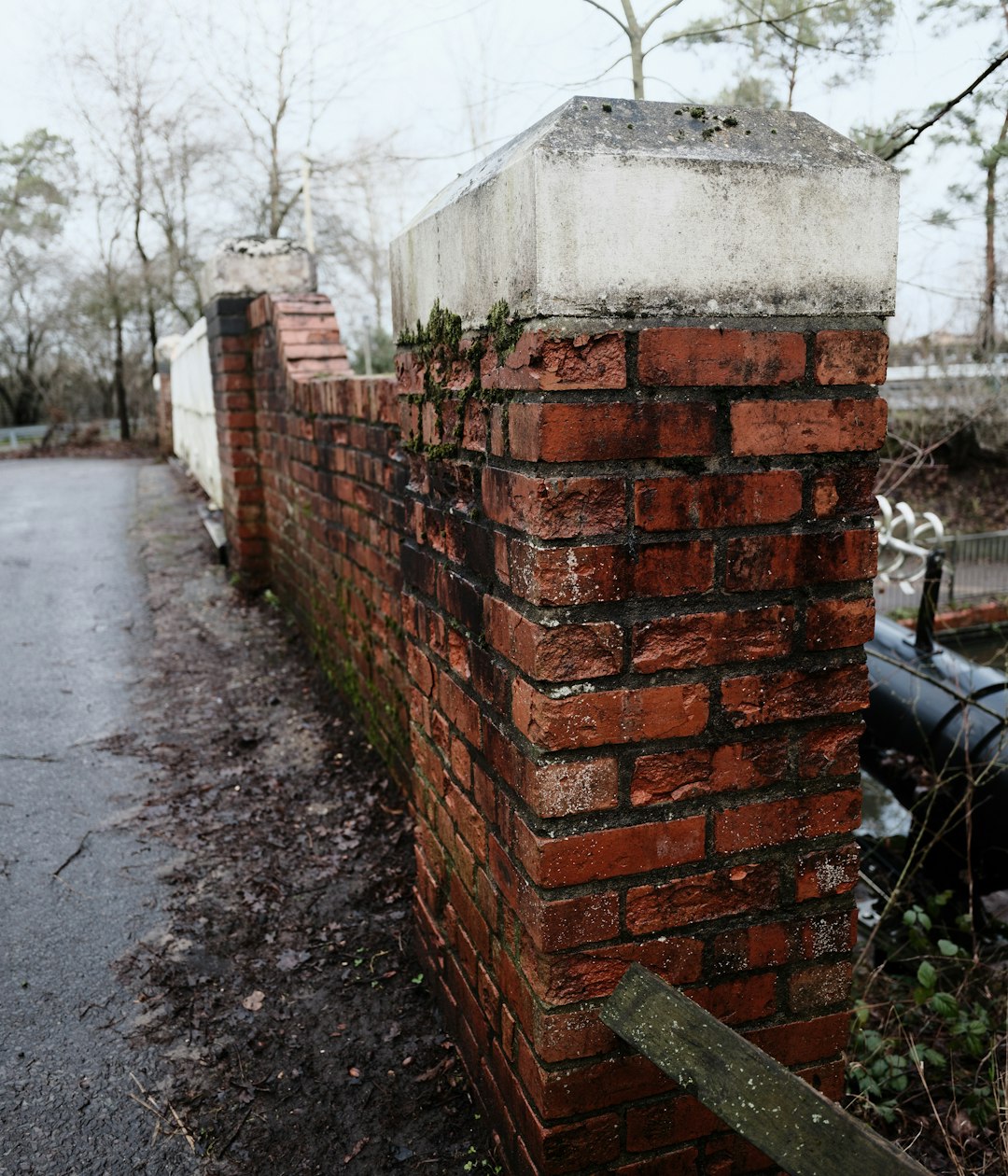 A weathered brick wall with a concrete cap